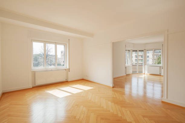 A living room before: an empty apartment with bare white walls and herringbone parquet